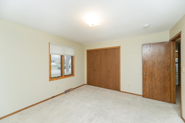 unfurnished bedroom with a closet and light colored carpet