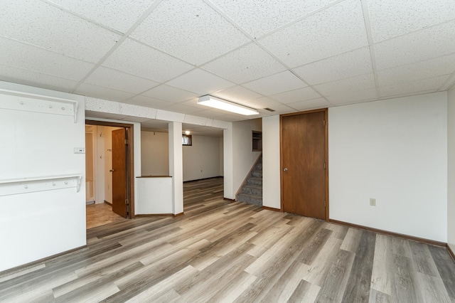 basement featuring light wood-type flooring and a paneled ceiling