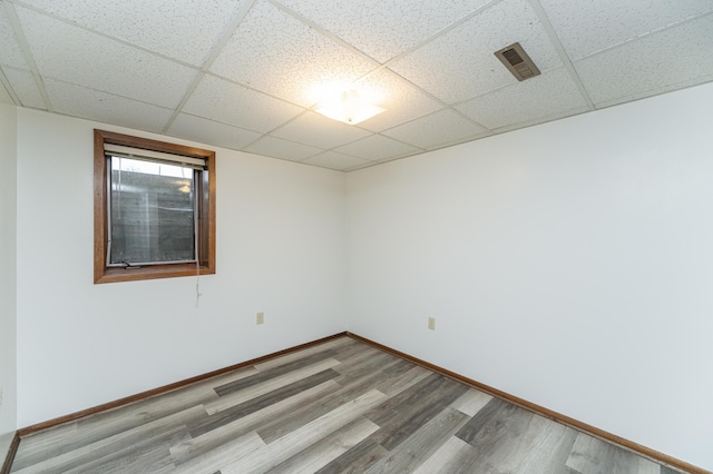 empty room featuring a paneled ceiling and light wood-type flooring