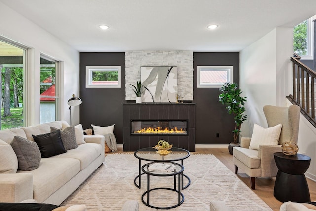 living room with a stone fireplace and light hardwood / wood-style flooring