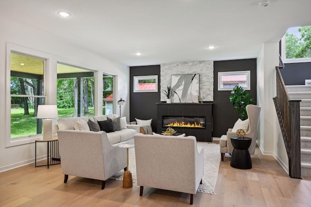 living room featuring a tiled fireplace, plenty of natural light, and light hardwood / wood-style floors