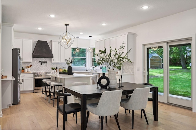 dining room featuring sink, an inviting chandelier, and light hardwood / wood-style flooring