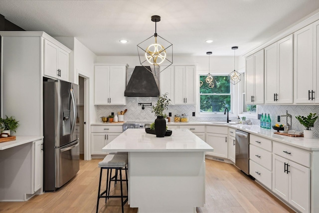 kitchen featuring white cabinets, stainless steel appliances, light hardwood / wood-style floors, and a kitchen island