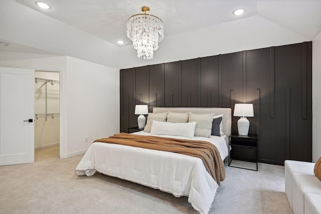 bedroom featuring light carpet, an inviting chandelier, a walk in closet, a closet, and vaulted ceiling