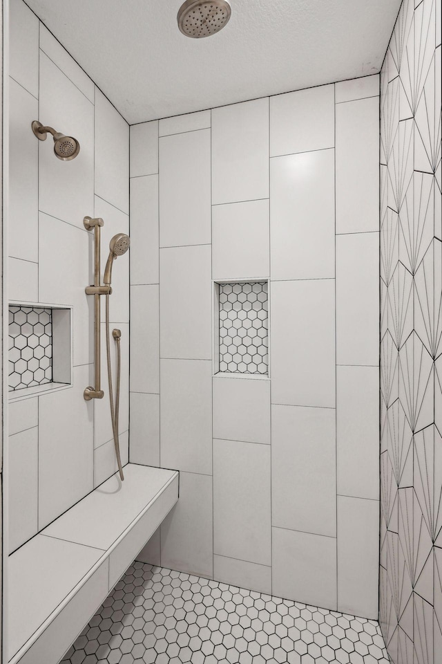 bathroom featuring a textured ceiling and a tile shower