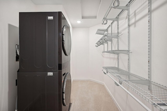 laundry area featuring stacked washer / dryer and carpet