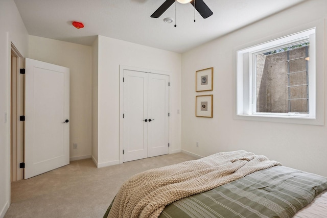 bedroom with light colored carpet, ceiling fan, and a closet