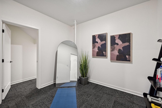 interior space featuring dark colored carpet and a textured ceiling