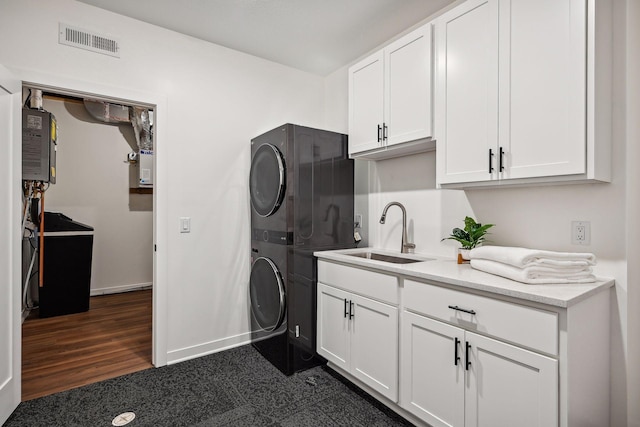 clothes washing area with dark hardwood / wood-style flooring, stacked washing maching and dryer, cabinets, and sink