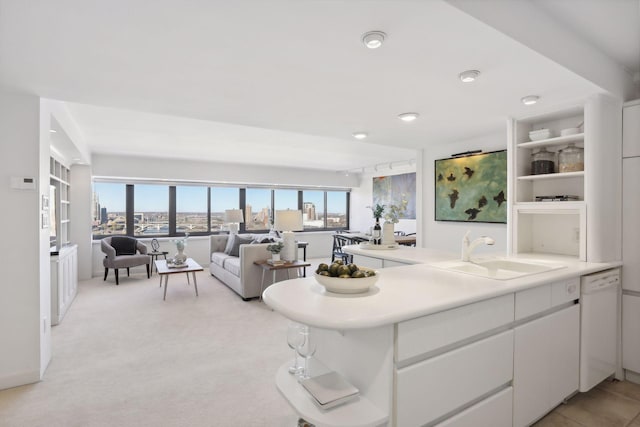 interior space with white dishwasher, a healthy amount of sunlight, white cabinetry, and sink