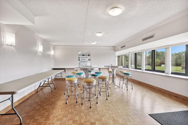 dining area with a textured ceiling and light parquet floors