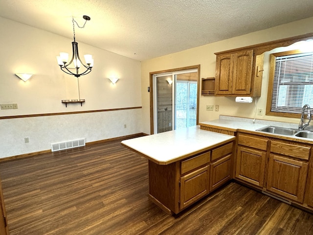 kitchen with pendant lighting, dark hardwood / wood-style floors, sink, and a textured ceiling