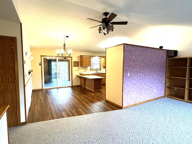 kitchen with ceiling fan with notable chandelier, sink, dark hardwood / wood-style floors, a textured ceiling, and decorative light fixtures