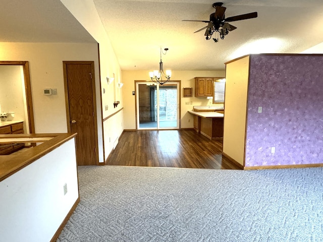 kitchen with a textured ceiling, ceiling fan with notable chandelier, dark wood-type flooring, and decorative light fixtures