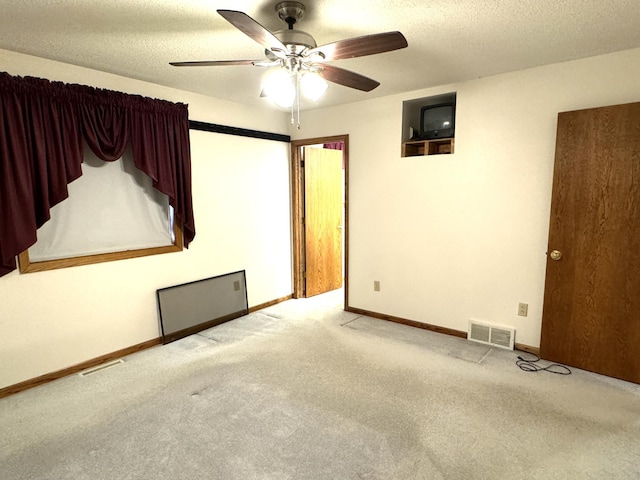 empty room featuring a textured ceiling, light colored carpet, and ceiling fan