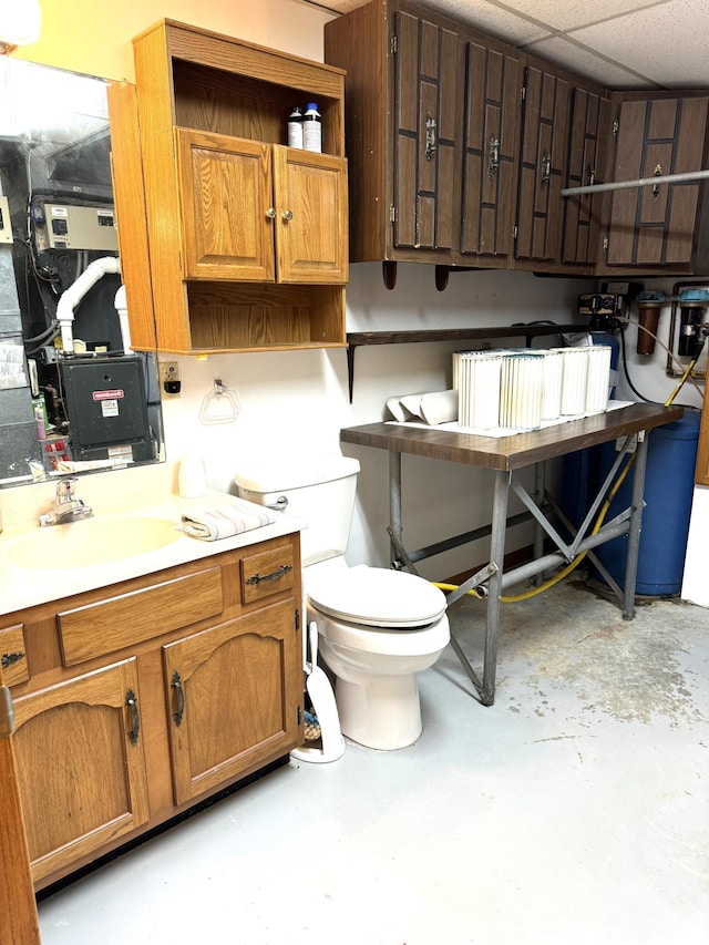 bathroom with sink, concrete floors, and a drop ceiling