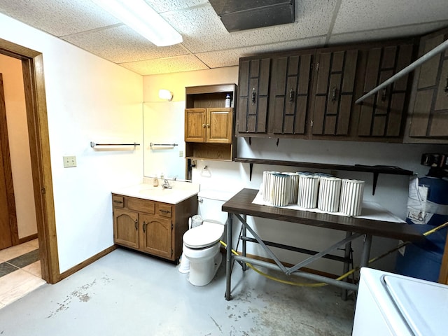 bathroom featuring a paneled ceiling, concrete flooring, and sink