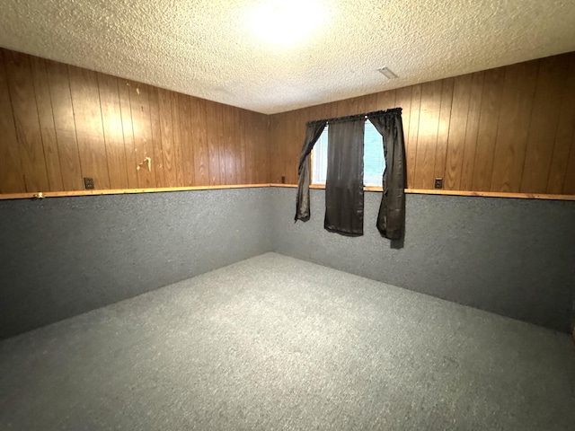 spare room featuring wood walls and a textured ceiling