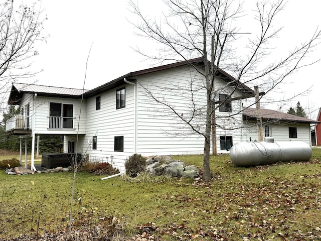 view of home's exterior featuring a lawn, a balcony, and a hot tub