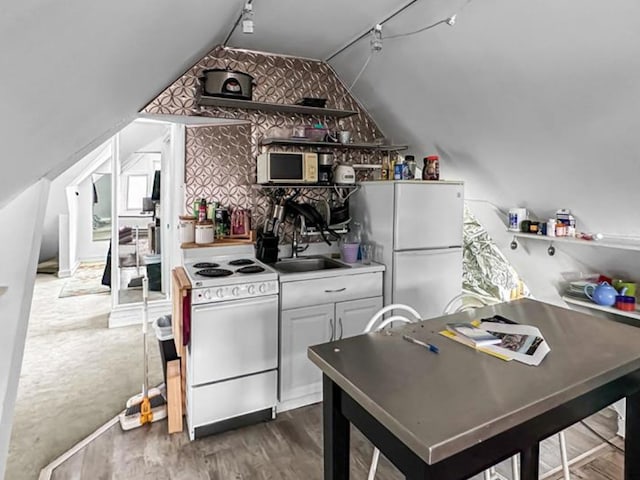 kitchen with lofted ceiling, rail lighting, a sink, wood finished floors, and white appliances