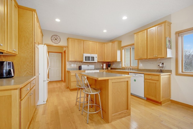 kitchen featuring light wood-type flooring, white appliances, a kitchen island, and plenty of natural light