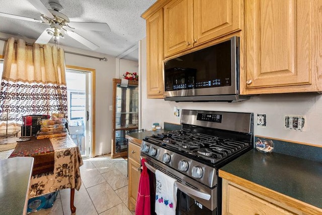 kitchen with a textured ceiling, stainless steel appliances, ceiling fan, and light tile patterned flooring