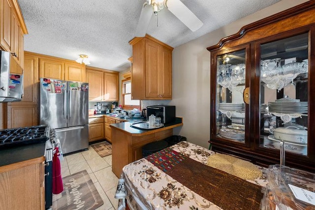 kitchen with stainless steel refrigerator, ceiling fan, light tile patterned floors, and a textured ceiling