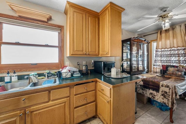 kitchen with a textured ceiling, ceiling fan, light tile patterned flooring, and sink