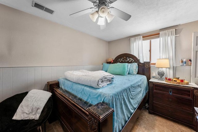 carpeted bedroom with a textured ceiling, ceiling fan, and wood walls