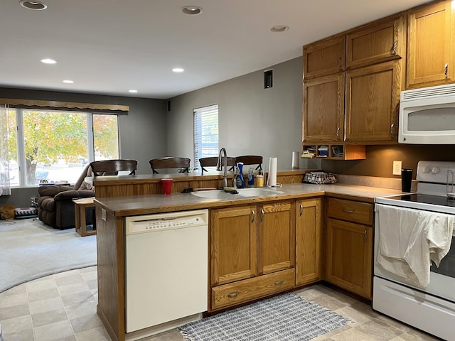 kitchen with a wealth of natural light, white appliances, sink, and kitchen peninsula