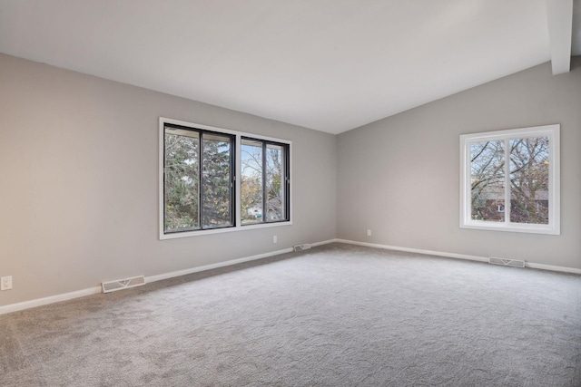 carpeted empty room with lofted ceiling with beams and a wealth of natural light