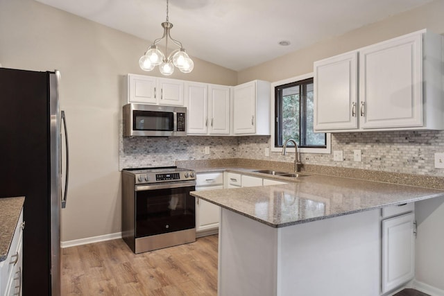 kitchen with stainless steel appliances, white cabinetry, pendant lighting, light hardwood / wood-style floors, and kitchen peninsula