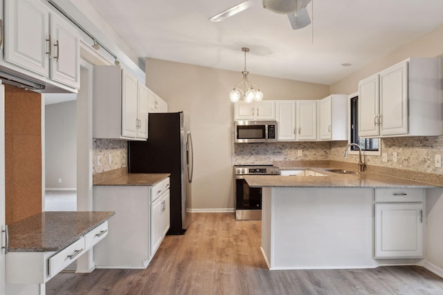 kitchen featuring lofted ceiling, sink, pendant lighting, appliances with stainless steel finishes, and white cabinetry