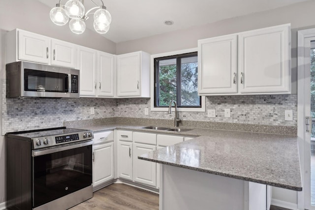 kitchen with sink, appliances with stainless steel finishes, light wood-type flooring, white cabinets, and pendant lighting