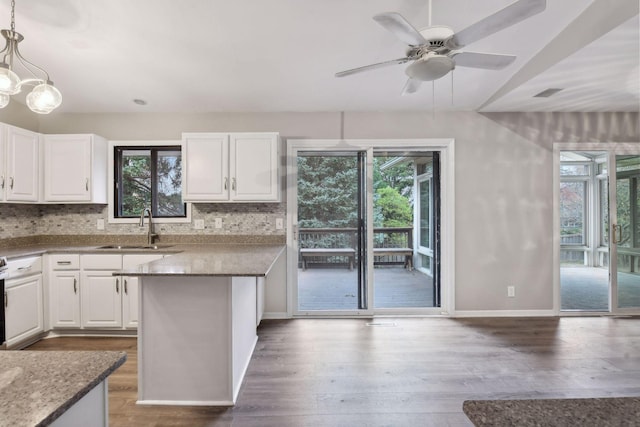 kitchen featuring white cabinets, hanging light fixtures, plenty of natural light, and dark stone countertops