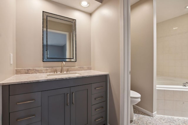 bathroom featuring toilet, vanity, and tiled tub