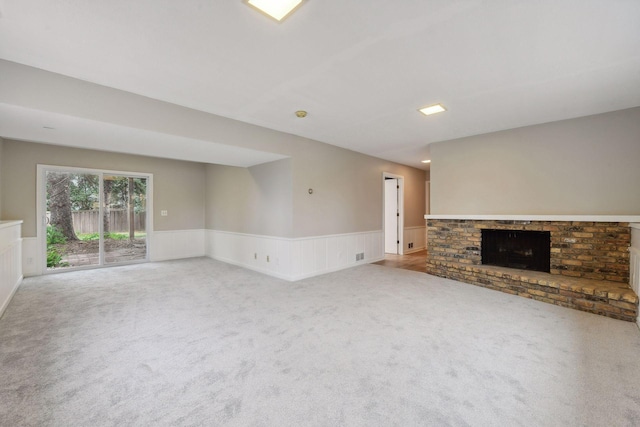 unfurnished living room featuring a brick fireplace and light carpet