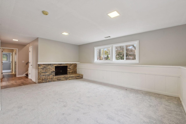 unfurnished living room featuring a brick fireplace and carpet floors