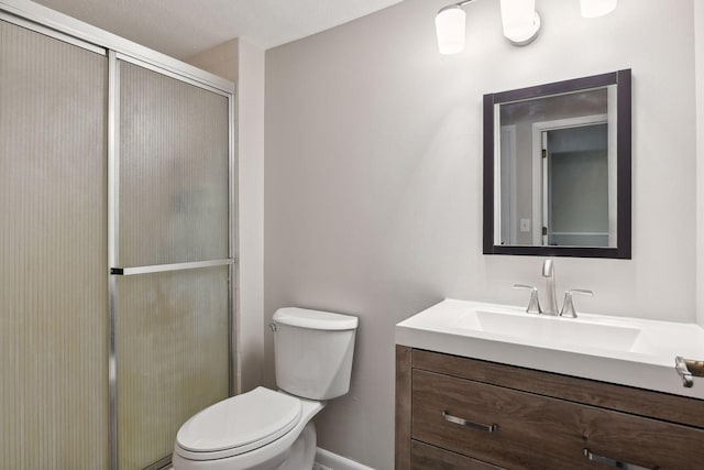 bathroom with vanity, a textured ceiling, toilet, and a shower with door