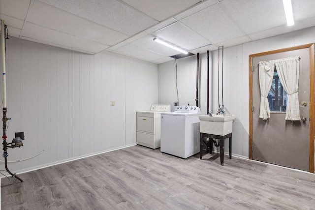 washroom with wooden walls, light wood-type flooring, and washer and clothes dryer