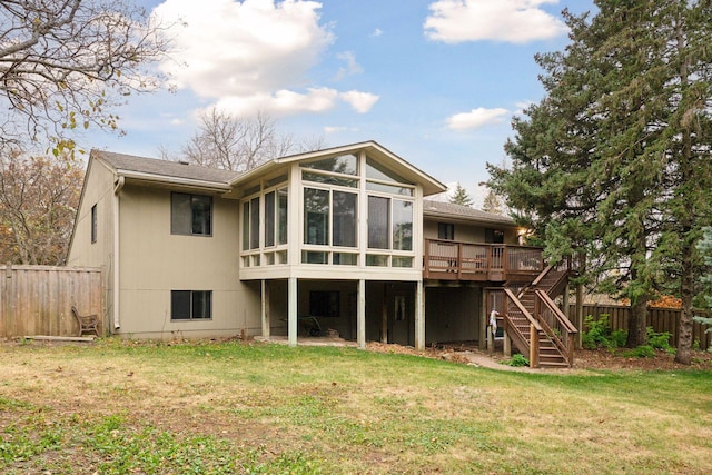 back of property with a sunroom, a yard, and a wooden deck