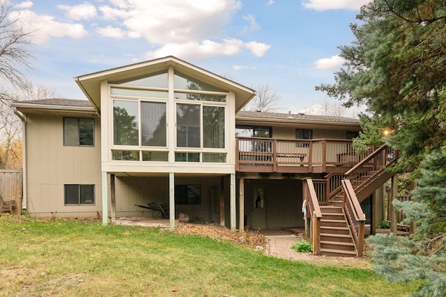 rear view of property featuring a deck, a lawn, and a sunroom