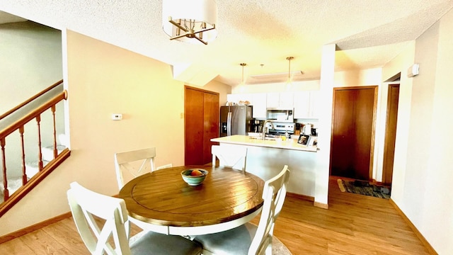 dining room featuring sink, a textured ceiling, light hardwood / wood-style flooring, and an inviting chandelier