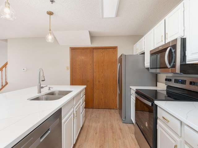 kitchen featuring stainless steel appliances, a textured ceiling, white cabinets, decorative light fixtures, and sink