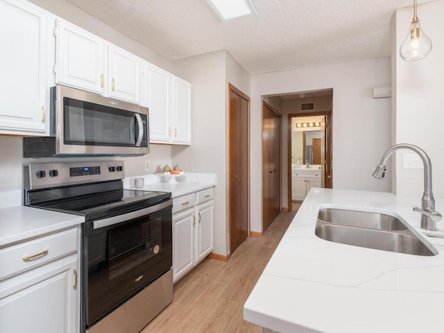 kitchen with stainless steel appliances, white cabinetry, sink, and pendant lighting