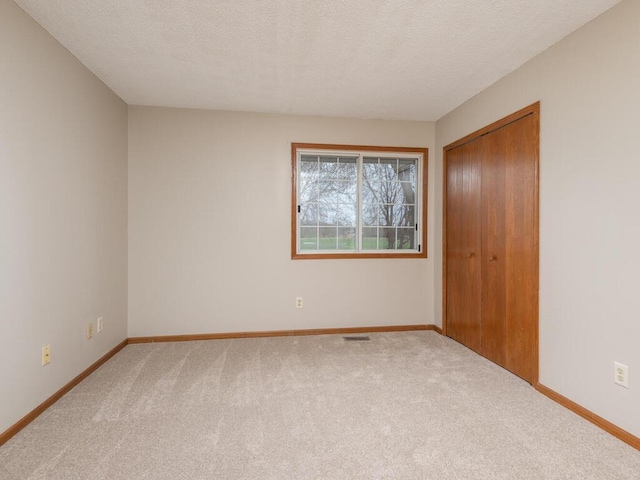 empty room featuring a textured ceiling and light carpet