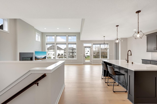 kitchen featuring sink, a kitchen bar, a kitchen island with sink, a notable chandelier, and light hardwood / wood-style floors