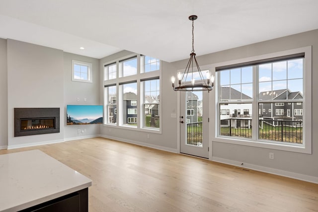 unfurnished dining area with an inviting chandelier and light hardwood / wood-style floors