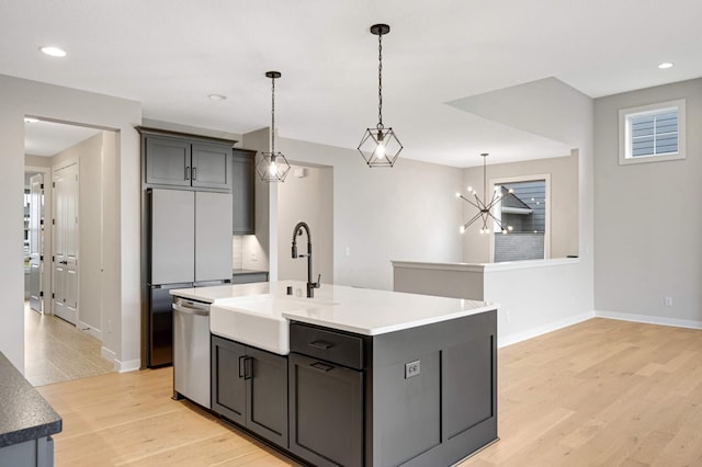 kitchen with sink, hanging light fixtures, an island with sink, stainless steel dishwasher, and light wood-type flooring