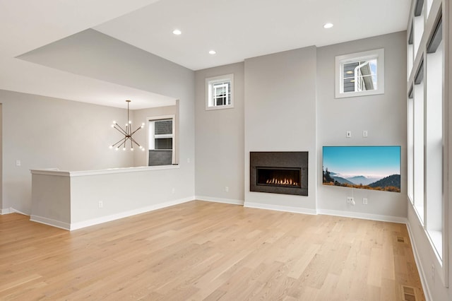 unfurnished living room featuring an inviting chandelier and light wood-type flooring